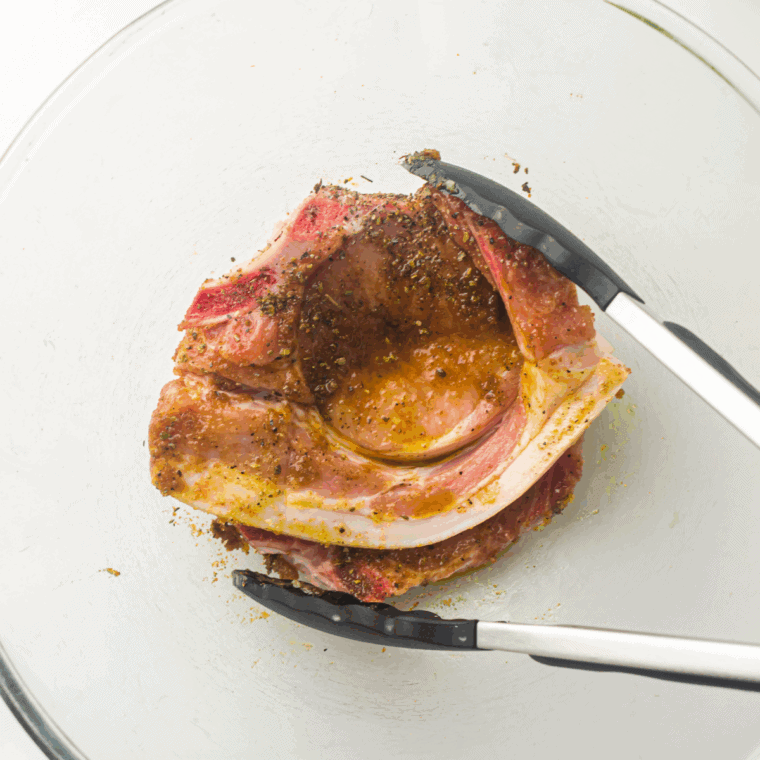 Brushing pork chops with olive oil and rubbing with chili, paprika, cumin, garlic, salt, and pepper.
