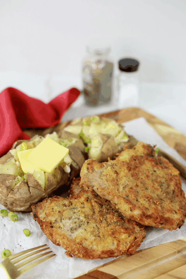Golden Parmesan-crusted pork chops on a plate, garnished and ready to serve