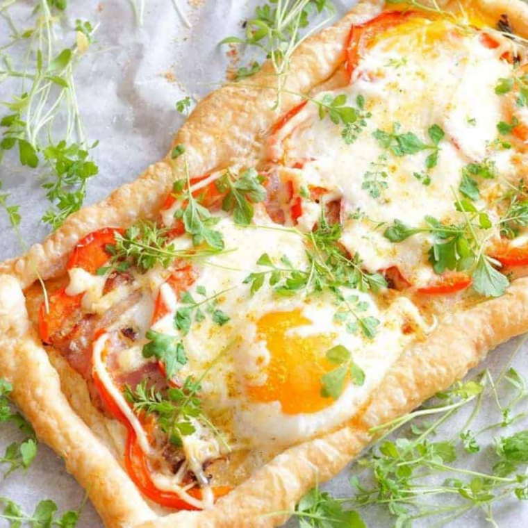 Golden crescent squares stuffed with bacon, scrambled eggs, and melted cheese in an air fryer basket