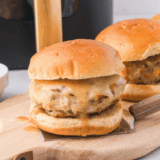 Juicy air fryer Greek chicken burger topped with tzatziki, tomato, and red onion on a toasted sesame bun