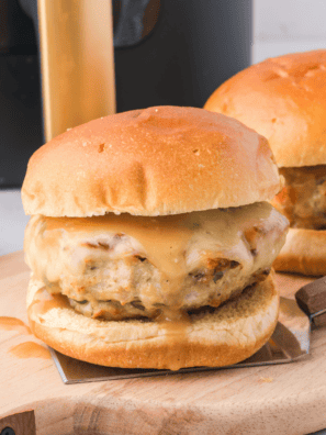 Juicy air fryer Greek chicken burger topped with tzatziki, tomato, and red onion on a toasted sesame bun