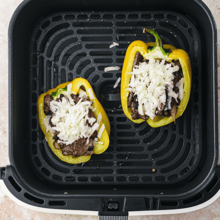 Stuffing bell peppers with steak and onions, topping with mozzarella, and air frying at 400°F for 3-5 minutes.