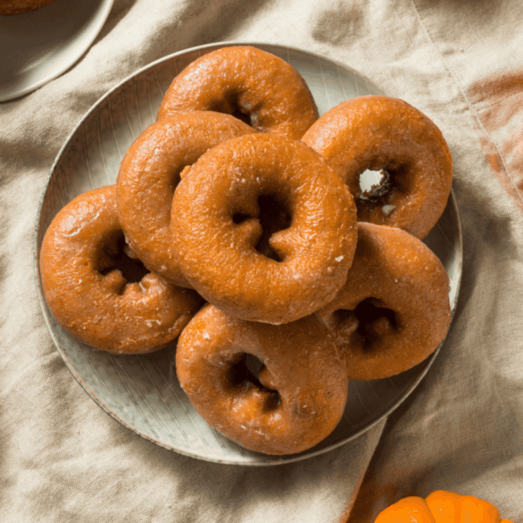Golden Easy Air Fryer Pumpkin Donuts topped with cinnamon sugar on a plate.