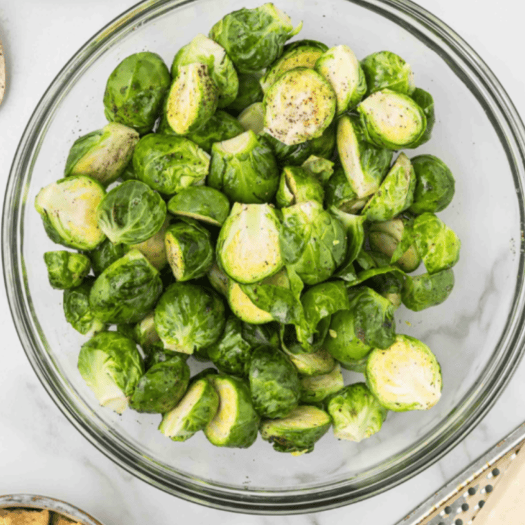 Halved and trimmed Brussels sprouts on a cutting board, prepped for the air fryer