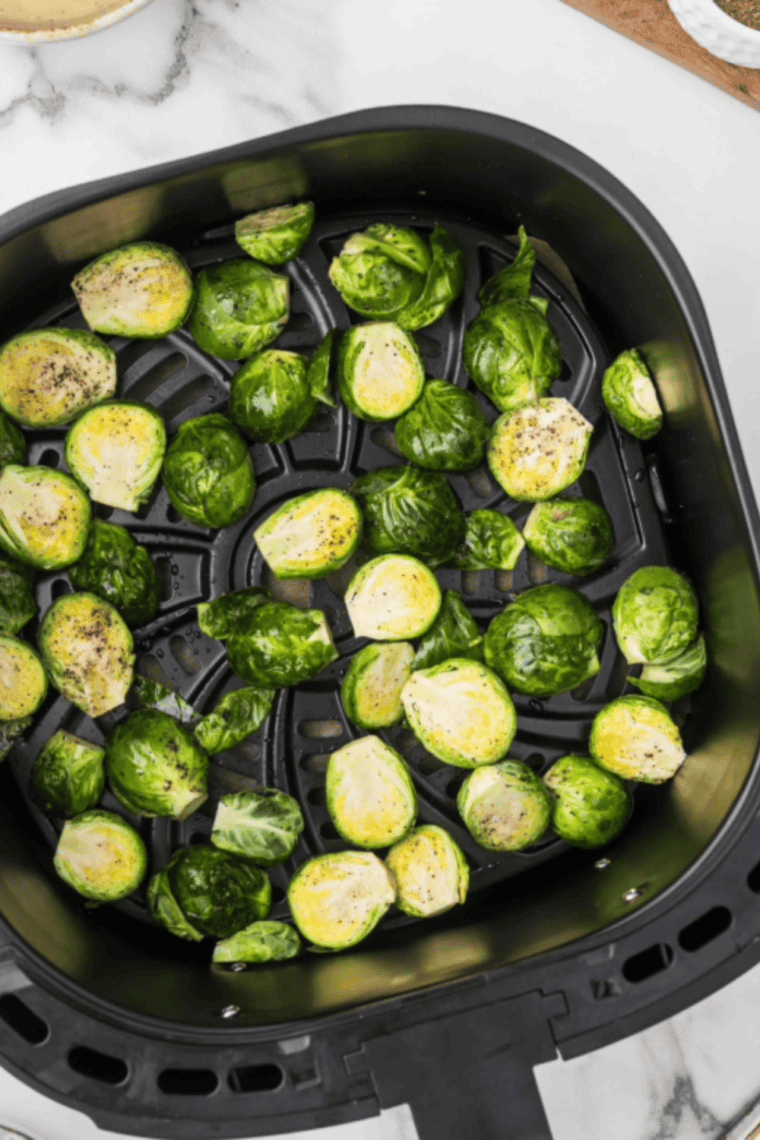 Seasoned Brussels sprouts in a single layer in the air fryer basket before cooking at 400°F