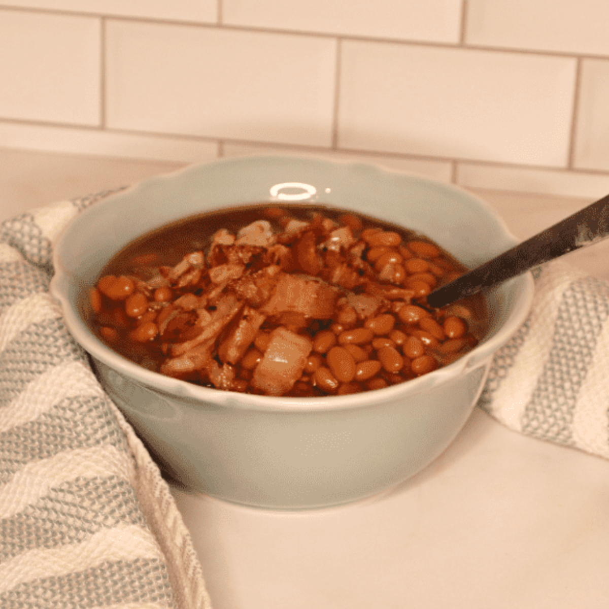 Mixing the cooked beans with the sautéed ingredients and sauce in a bowl.
