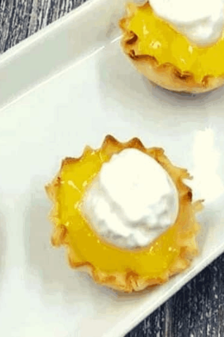 Air fryer mini lemon tarts with golden crusts and creamy lemon filling, garnished with lemon zest.