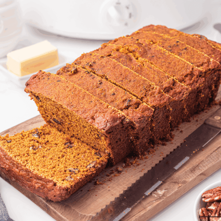 Freshly baked Bob Evans Pumpkin Bread sliced on a wooden cutting board, showing its moist, golden-orange texture and rich pumpkin spice aroma.