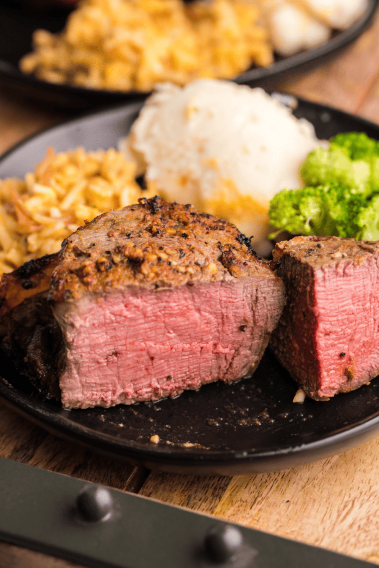Air fryer bacon-wrapped filet mignon on a plate, crispy bacon and perfectly cooked steak ready to serve.