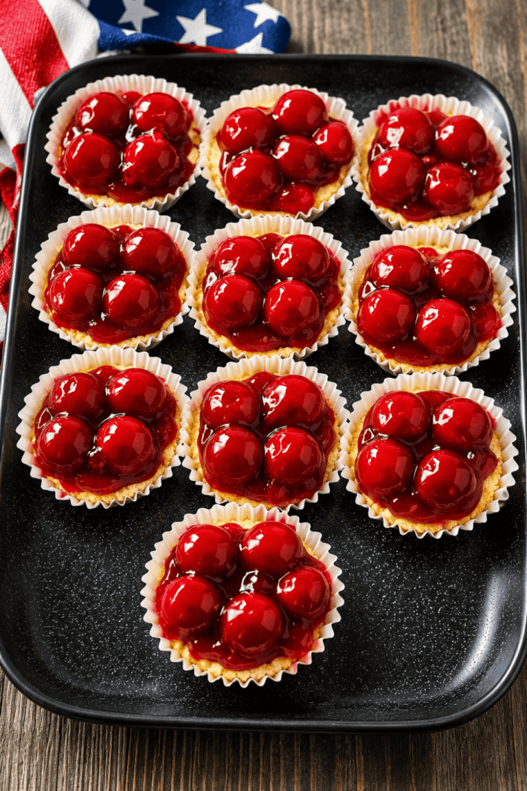 Plate of air fryer cherry cheesecake cupcakes topped with cherry pie filling