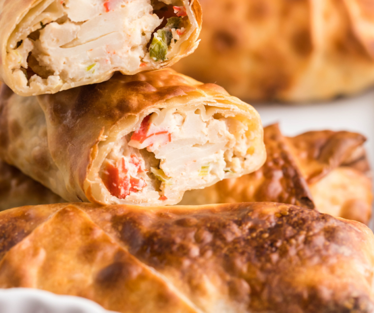 Close-up of Air Fryer Crab Rangoon Egg Rolls with a crispy golden-brown exterior, filled with creamy crab filling, and served with a side of dipping sauce.