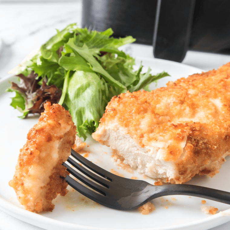 Golden brown Air Fryer Ritz Cracker Chicken, crispy on the outside and juicy on the inside, served on a plate garnished with fresh herbs.