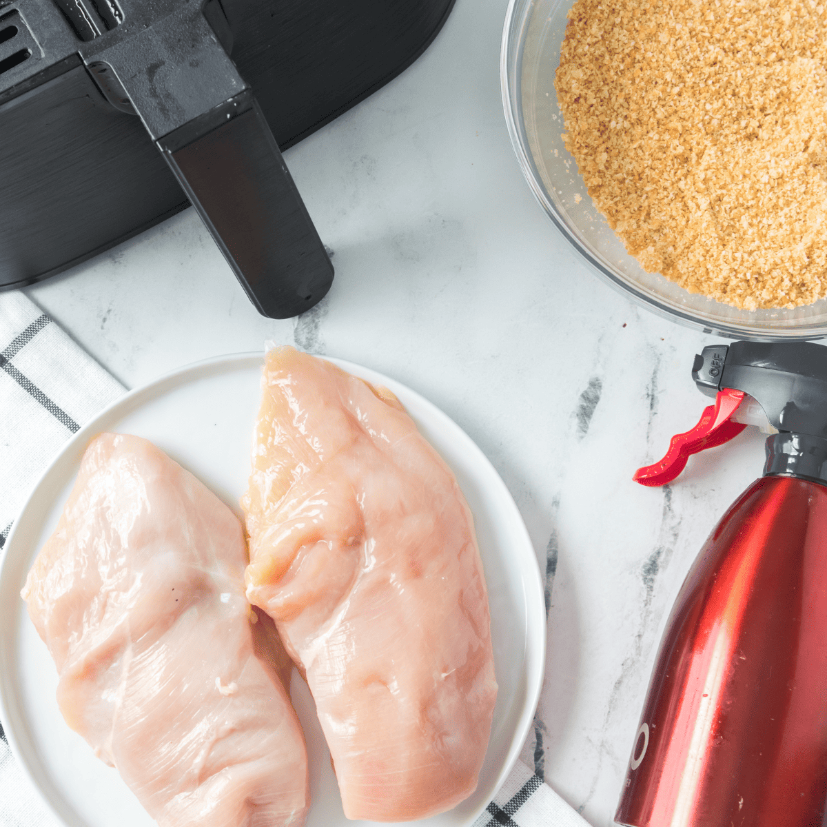 Ingredients for Air Fryer Ritz Cracker Chicken: chicken breasts, crushed Ritz crackers, egg, seasoning, and optional herbs.