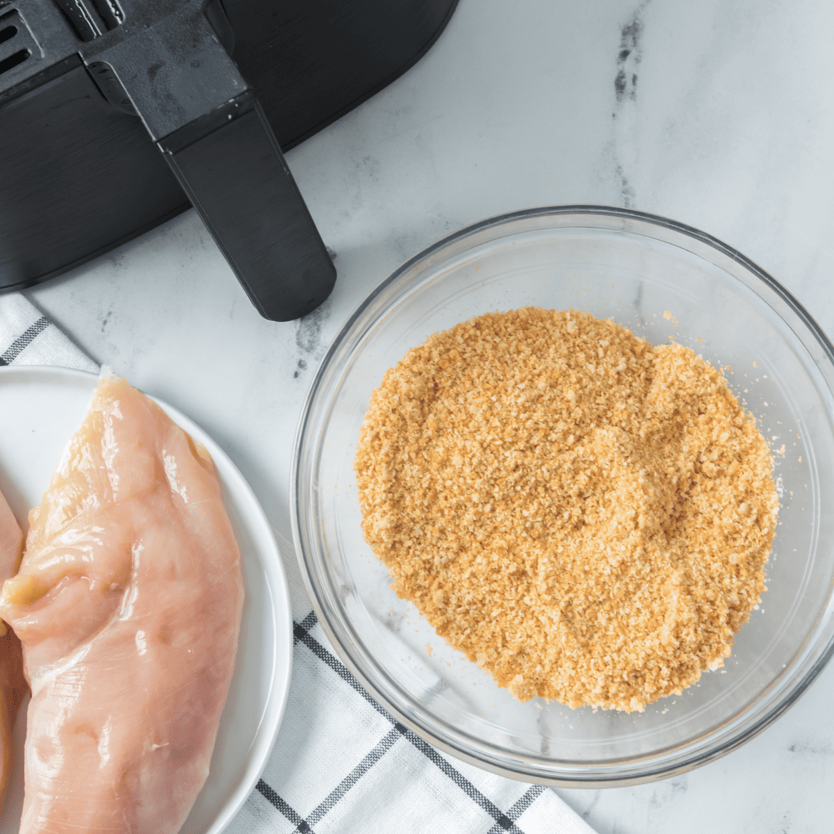 Prepare the chicken breasts by trimming and seasoning them for the Ritz Cracker coating.