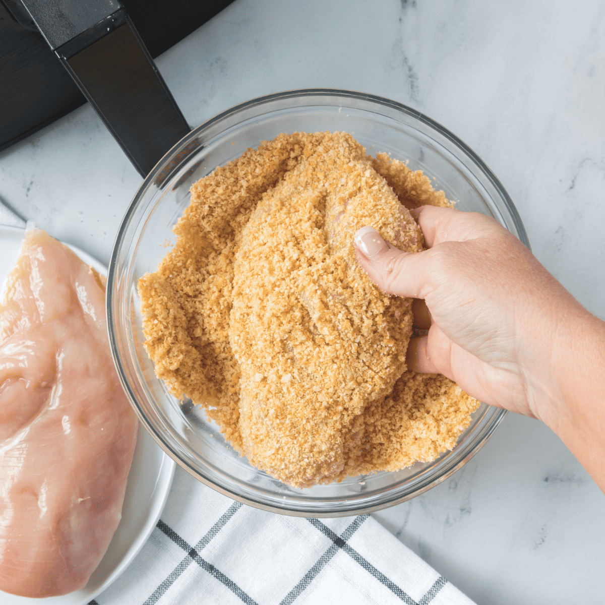 Dip each seasoned chicken breast in beaten egg for an adhesive layer before coating.