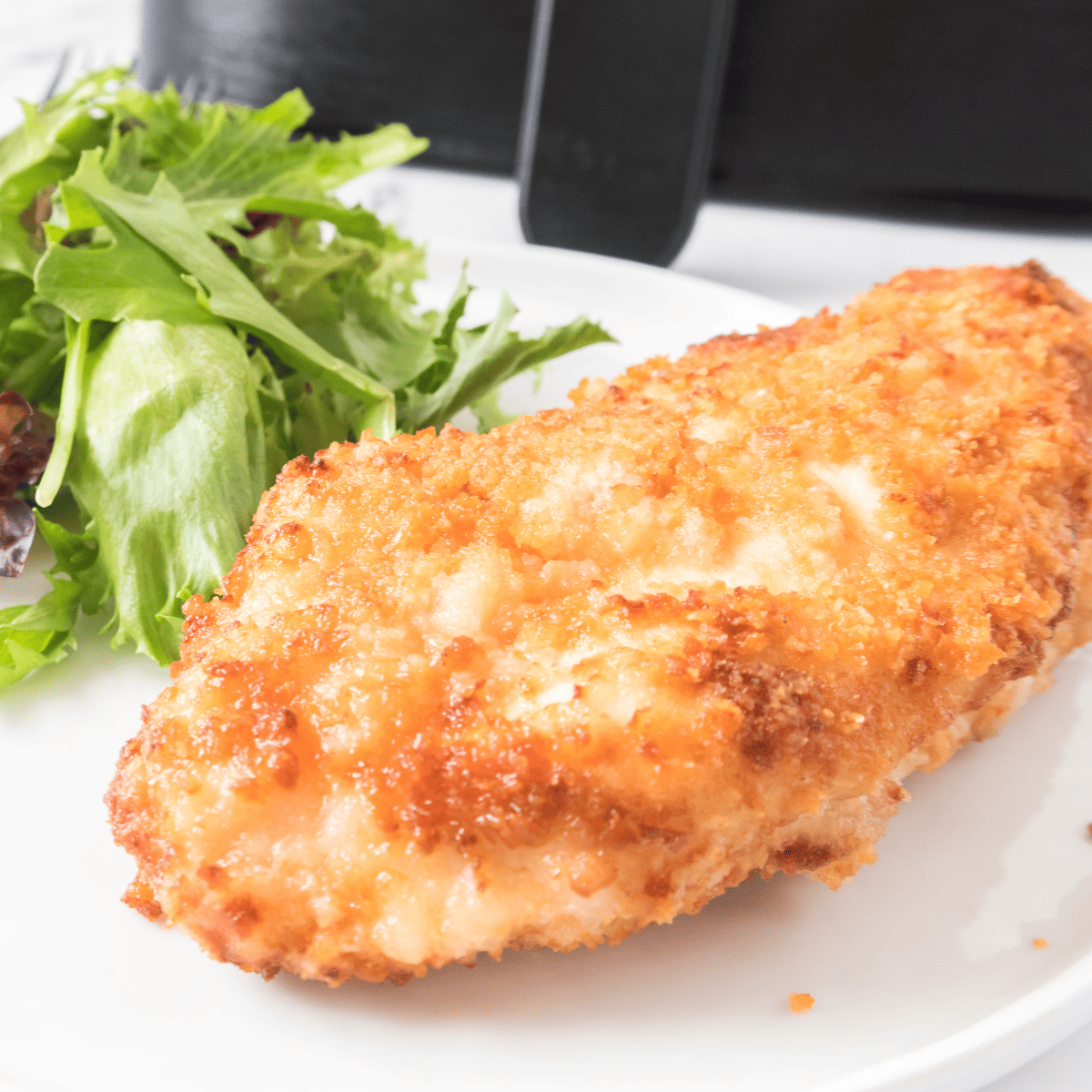 Crispy air-fried chicken coated in crushed Ritz crackers, garnished with fresh herbs, displayed on a serving platter with a side of dipping sauce.