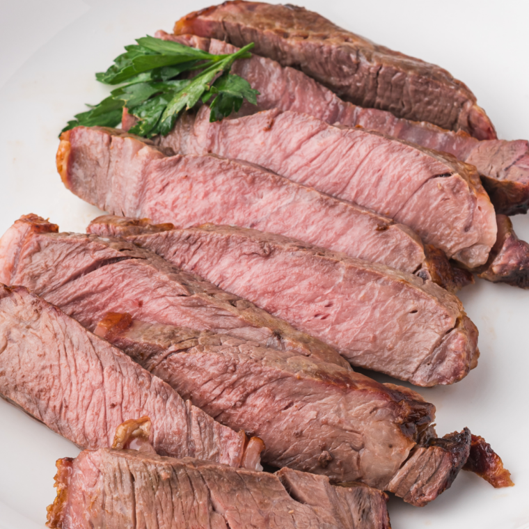 Ninja Crispi steak sliced against the grain on parchment, showing an even medium-rare center