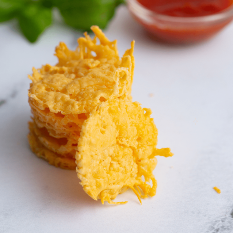 Hand holding an air fryer cheese crisp showing its thin, lacy texture