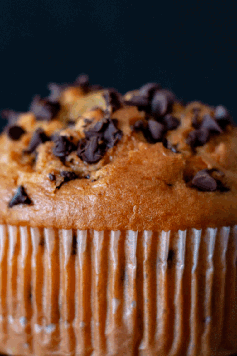 A fluffy, single-serve air fryer chocolate chip muffin with a bite taken out, showing the soft interior texture and chocolate chunks.