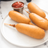 air fryer corn dogs on a plate with a side of ketchup