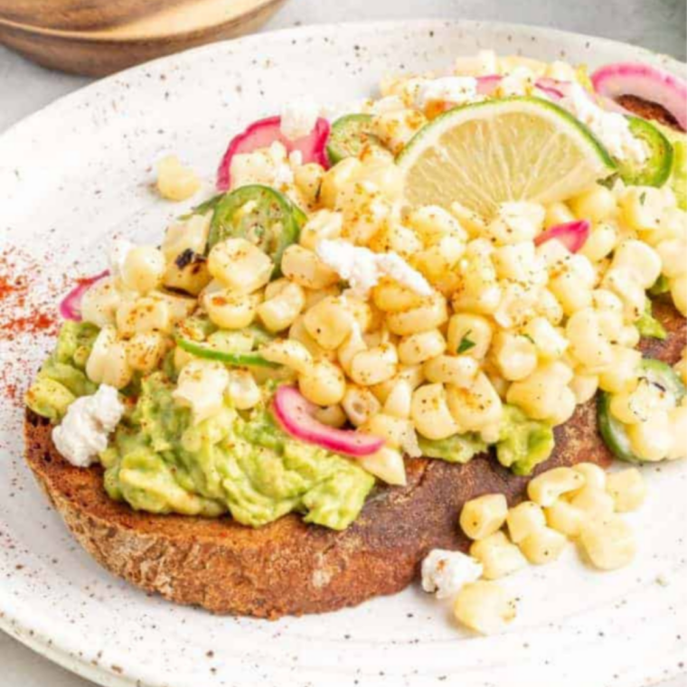 Air fryer egg in a hole with creamy avocado sauce, corn, and chili seasoning