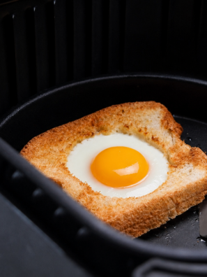 Air fryer egg in a hole on a white plate with a runny yolk running onto crispy buttered toast