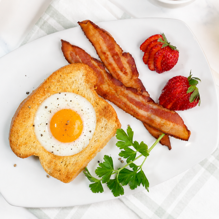 Air fryer egg in a hole with a runny yolk on a white plate with bacon and strawberries