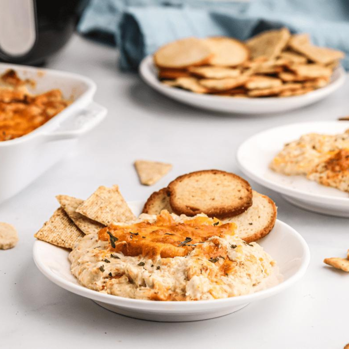 Deliciously creamy Air Fryer Hot Crab Dip served in a bowl, garnished with fresh herbs, and accompanied by crispy crackers.