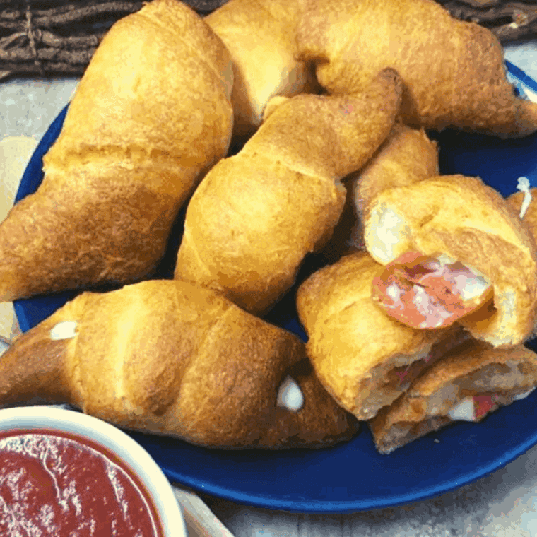 Golden crescent rolls filled with melted cheese and pepperoni, cooked in the air fryer and served with marinara sauce.
