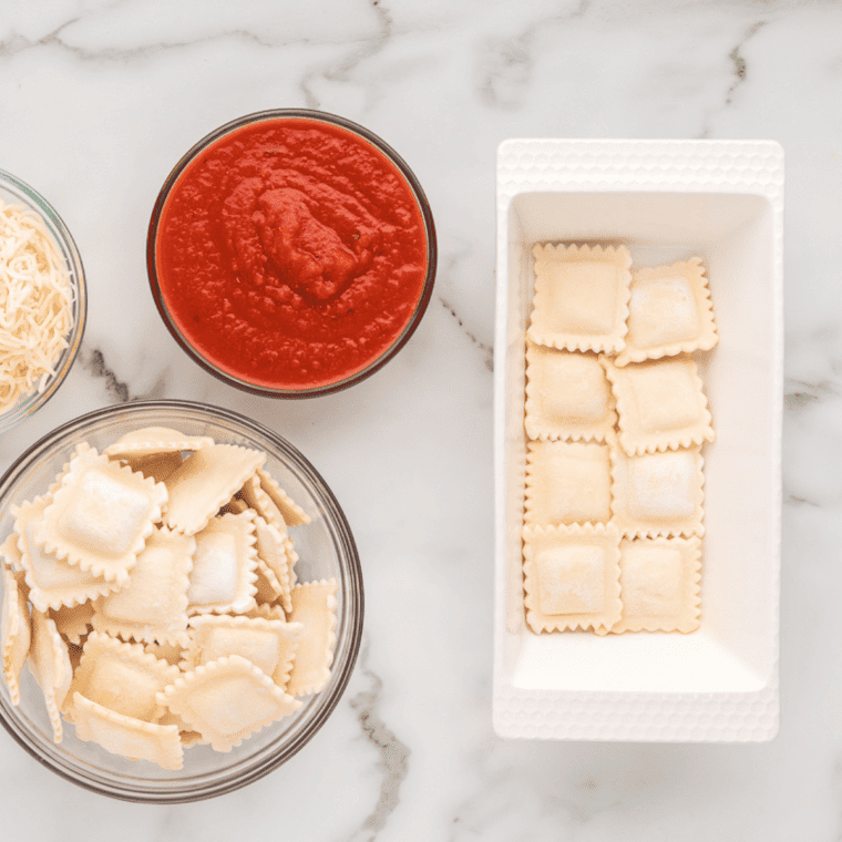 Frozen ravioli arranged in a single layer in an air fryer pan.