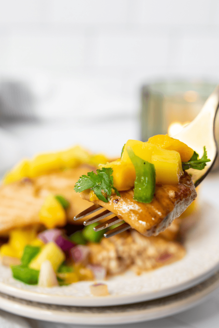 Juicy air fryer swordfish steak topped with fresh mango salsa and garnished with herbs.