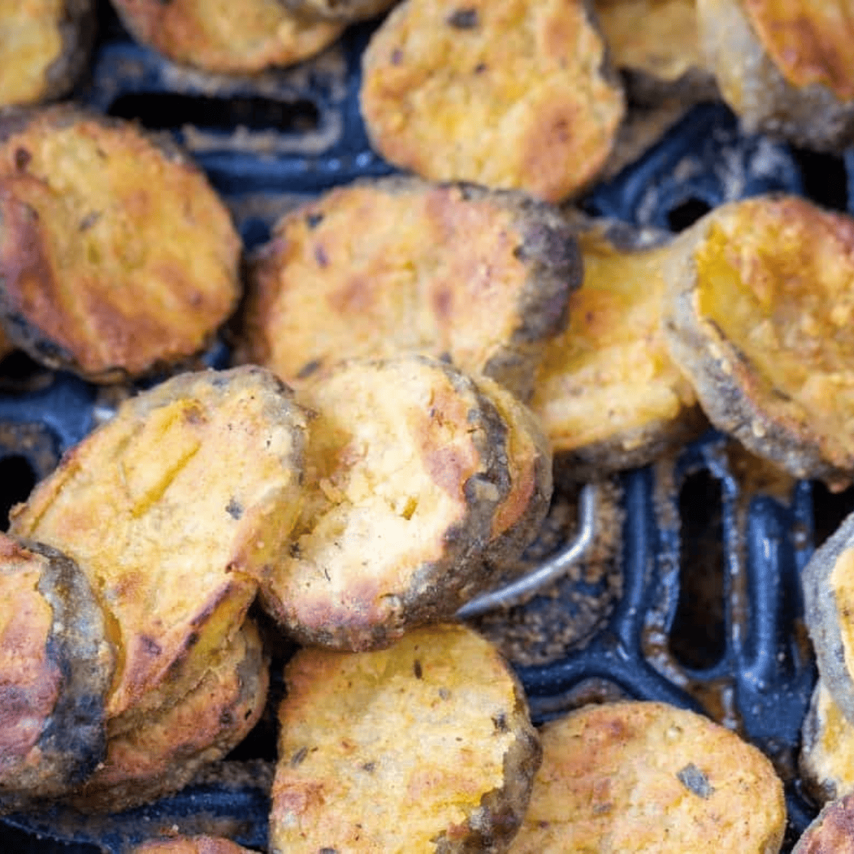 Air Fryer Basket with cooked pickles inside.