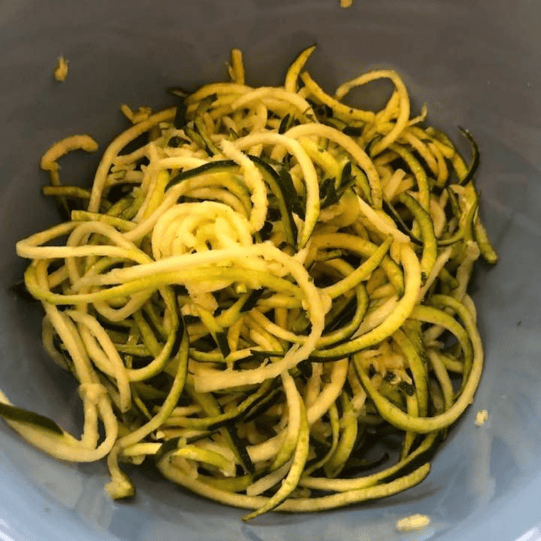 Zucchini noodles resting on a towel, releasing excess water.