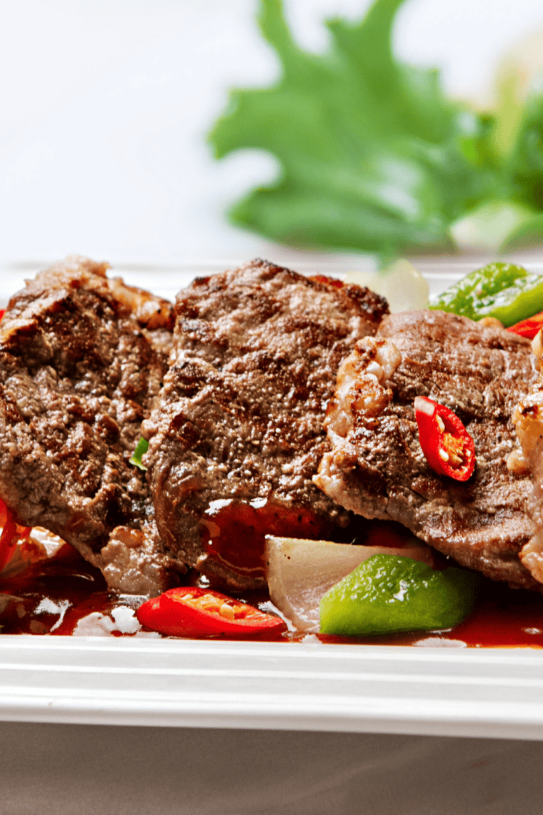 Sliced sirloin tip roast served on a platter with roasted vegetables and herbs, juicy beef cut showing tender interior.