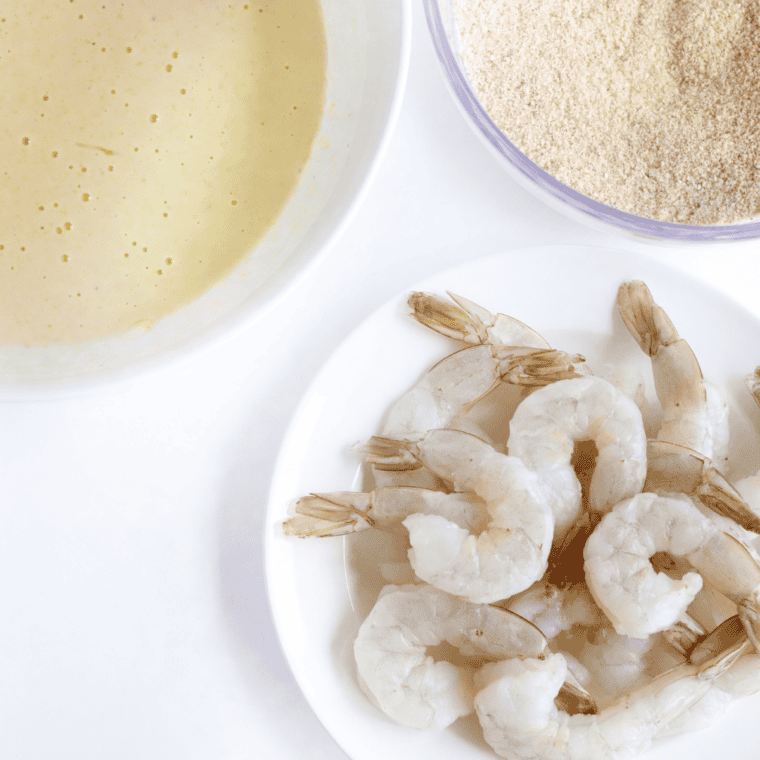 raw shrimp being patted dry and lightly coated in flour before battering”
