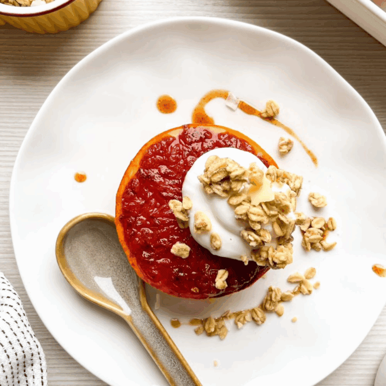 Caramelized air fryer grapefruit halves with golden edges served on a white plate.