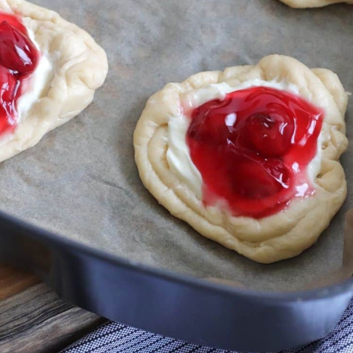Spreading cream cheese mixture and adding cherry pie filling to dough.