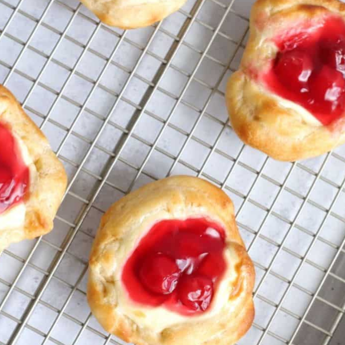 Placing cherry cream cheese Danish in air fryer basket for cooking.