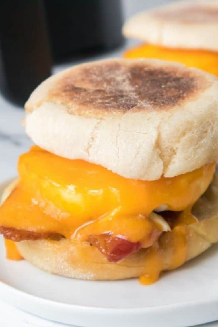 Air Fryer Egg McMuffin layered with sausage, a cooked egg, and melted cheese on a toasted English muffin