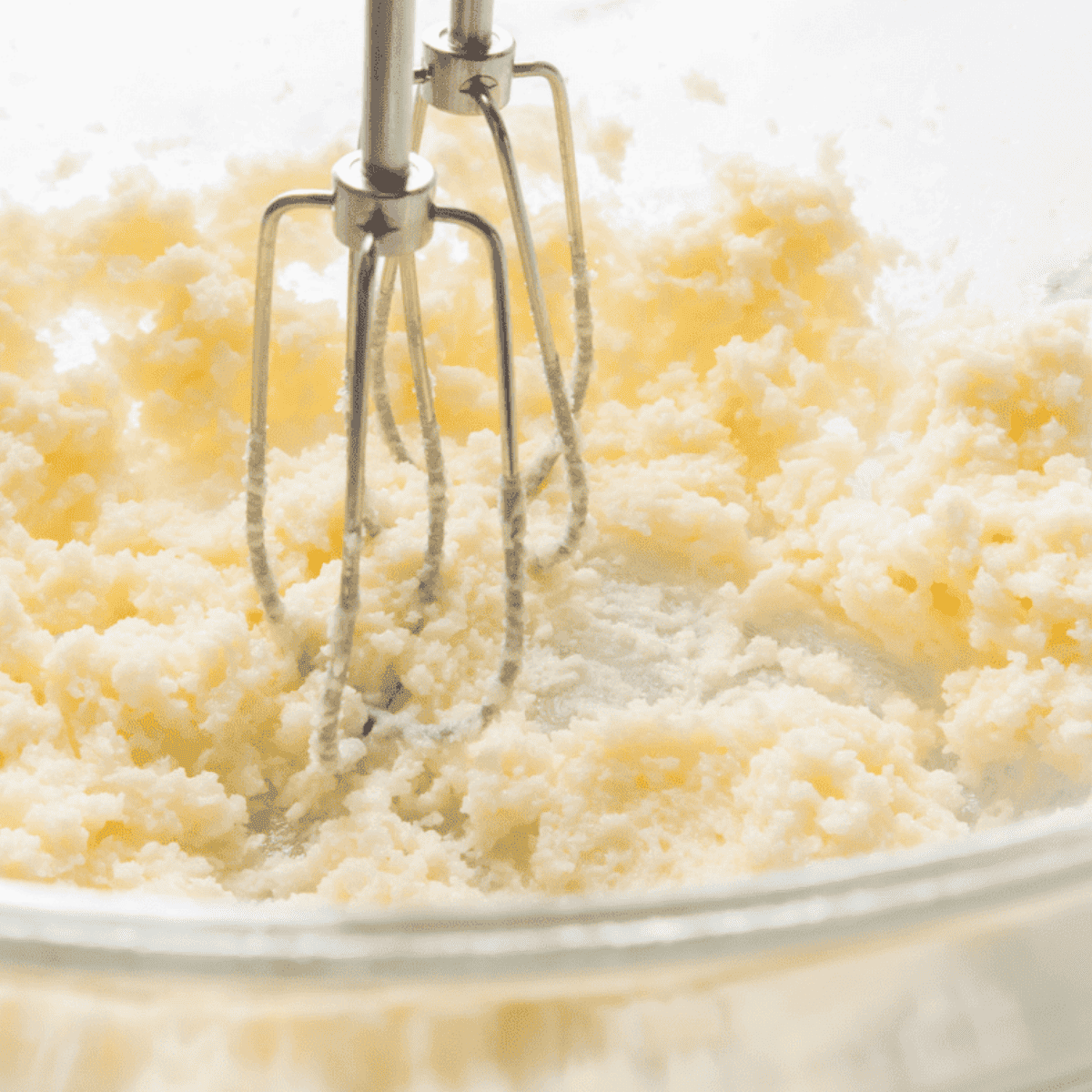 Mixing lemon loaf batter with butter, sugar, eggs, and lemon zest in a bowl