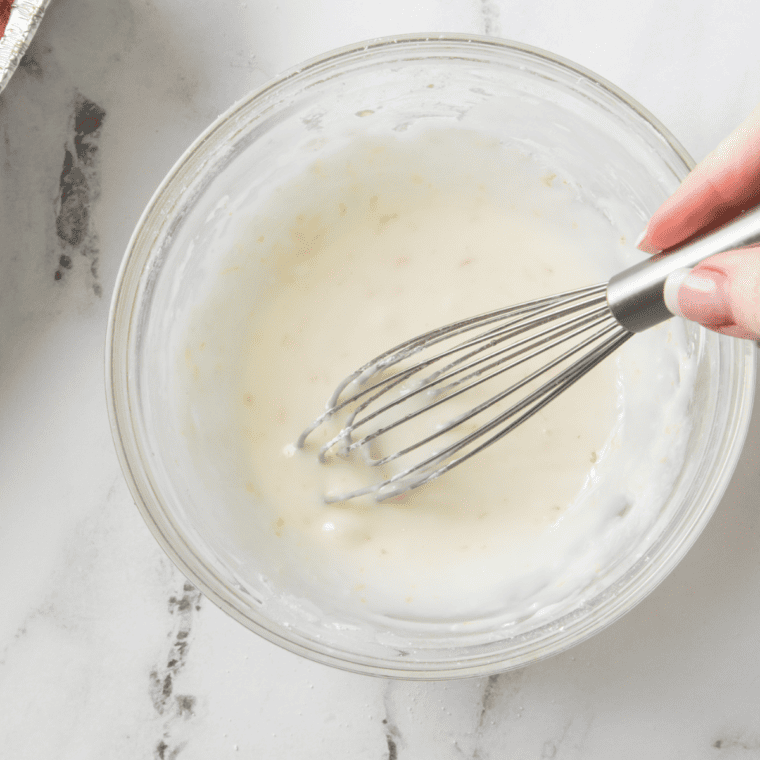 Spreading lemon icing over cooled air fryer lemon loaf
