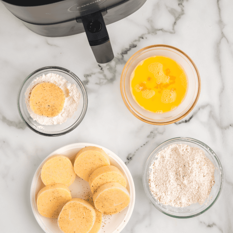Polenta rounds seasoned, coated in flour, dipped in egg, and dredged in breadcrumb mixture.