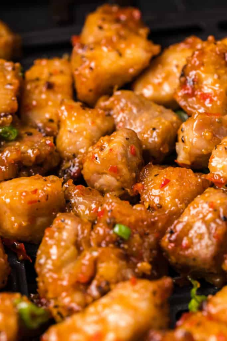 Golden crispy pork belly bites garnished with green onions.