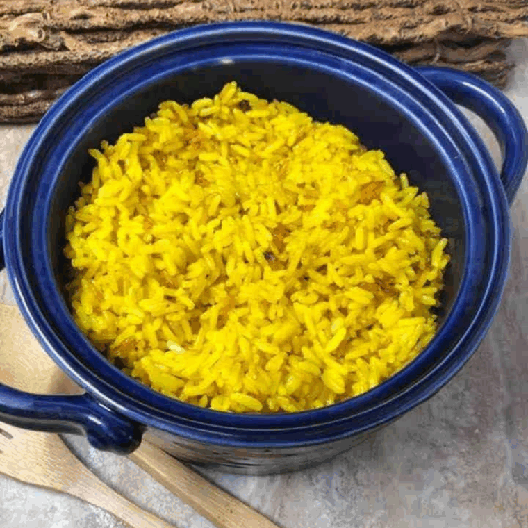 Fluffy Instant Pot Goya yellow rice served in a white bowl with fresh herbs.