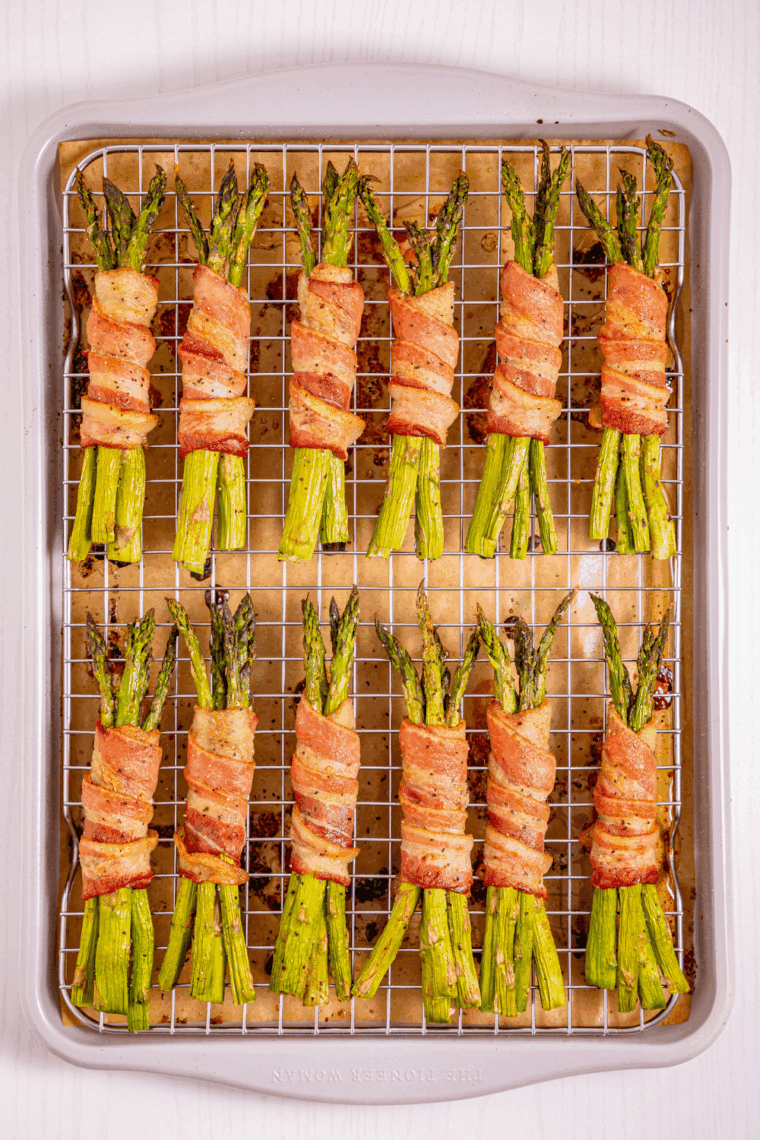 Arranging bacon-wrapped asparagus bundles in a single layer in air fryer basket.