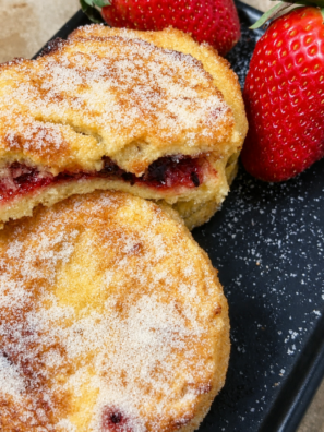 Jam stuffed French toast coated in sugar with raspberry jam showing through the center