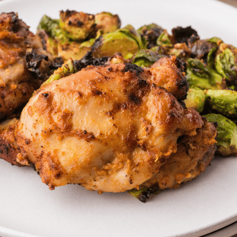 Finished air fryer balsamic glazed chicken thighs plated with glossy glaze spooned over