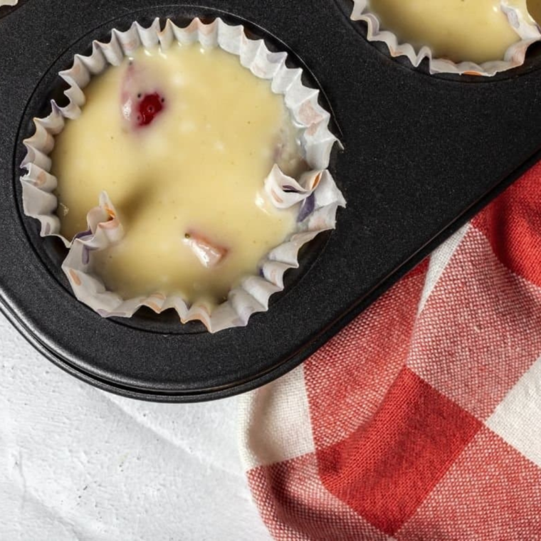 Folding cranberries into batter and pouring into greased muffin liner