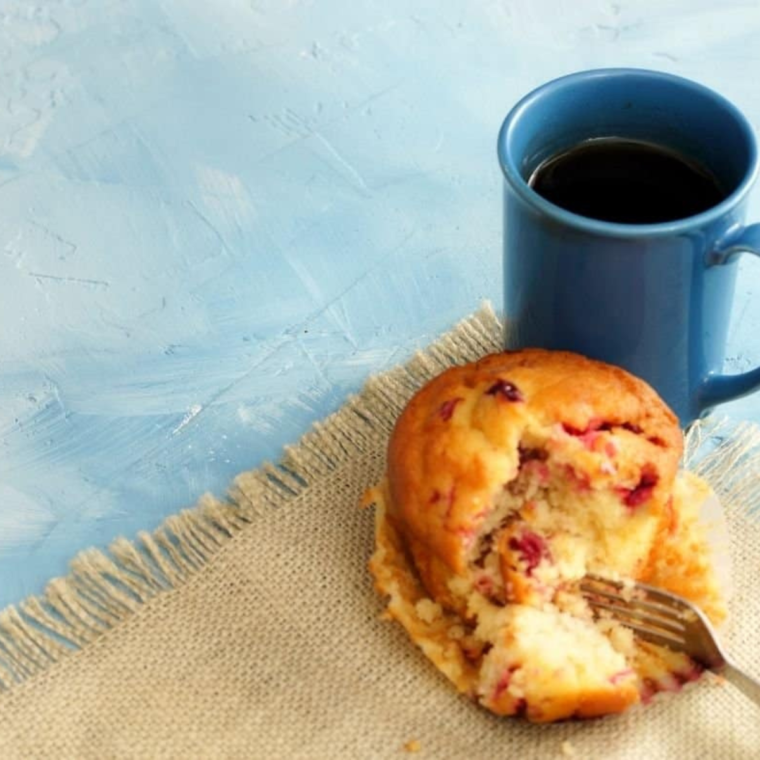 Single serve cranberry muffin made in air fryer with golden top and visible cranberries baked in a small muffin liner.