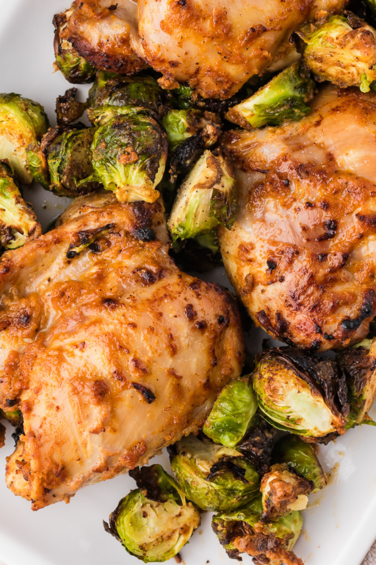 Air fryer honey balsamic Brussels sprouts halves, browned and glazed, served in a shallow bowl with a serving spoon